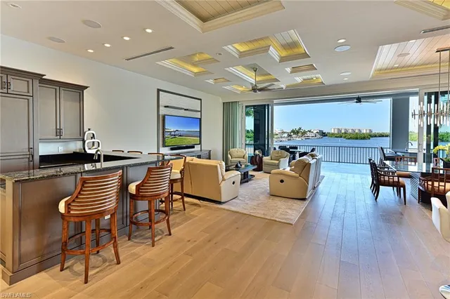 a living room with lots of furniture wooden floor and a large window
