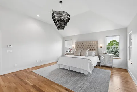 a spacious bedroom with a large bed and a chandelier