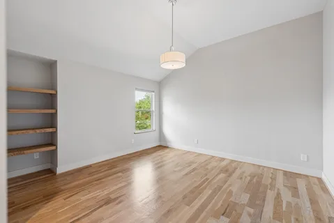 a view of an empty room with a window and wooden floor