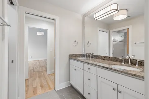 a bathroom with a granite countertop double vanity sink and a mirror
