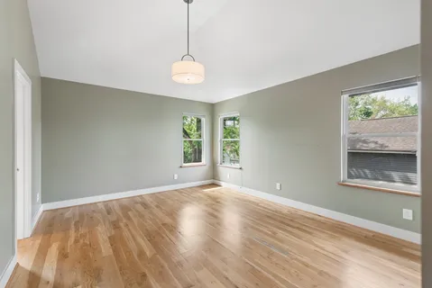 a view of an empty room with a window and wooden floor