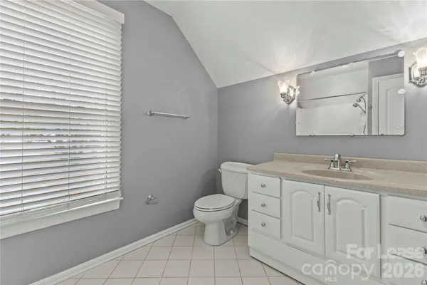 a bathroom with a granite countertop toilet a sink and a mirror