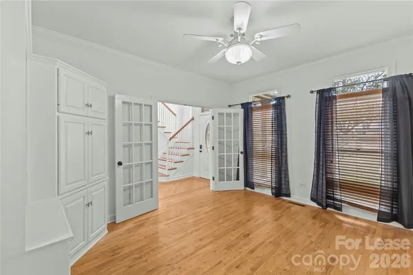 a view of empty room with wooden floor and fan