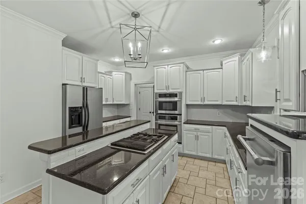 a kitchen with granite countertop a stove chairs and refrigerator