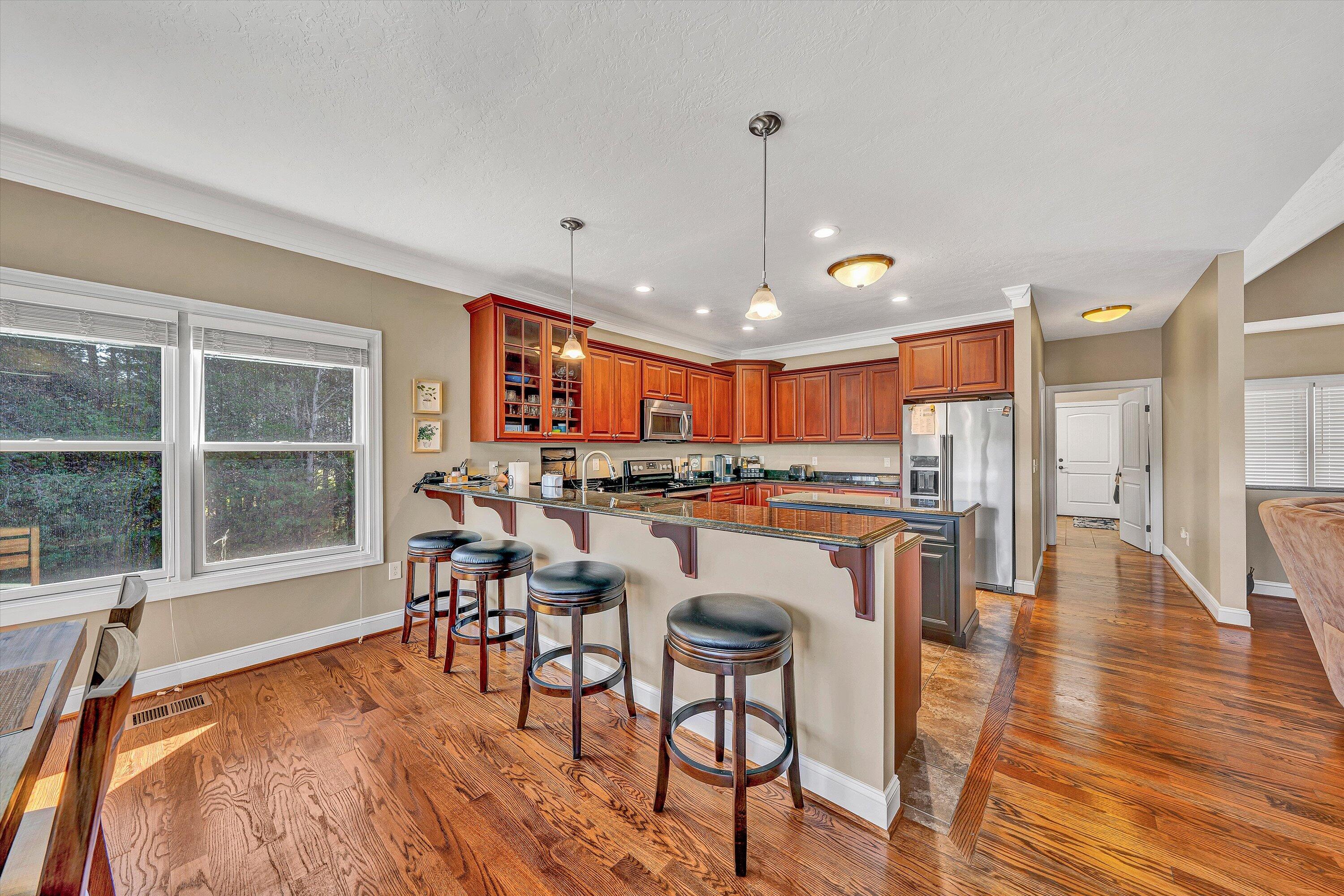 440 Augusta Way Wirtz, VA 24184 - Photo 13 of 63 a kitchen with stainless steel appliances granite countertop a stove top oven a refrigerator a dining table and chairs with wooden floor