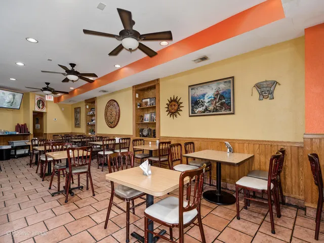 a dining hall with couches a dining table and chairs with a bookshelf