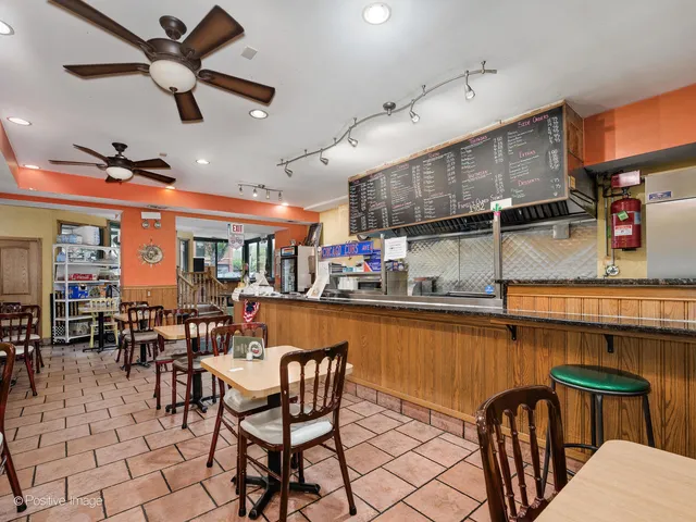 a dining hall with stainless steel appliances kitchen island granite countertop a dining table and chairs with the wooden floor