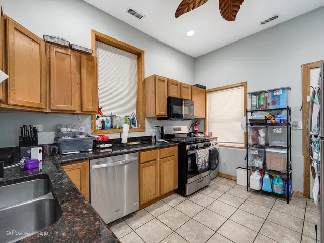 a kitchen with stainless steel appliances granite countertop a stove top oven a sink dishwasher and a refrigerator