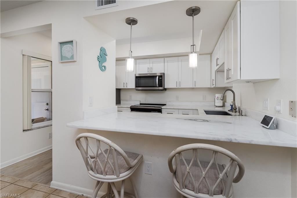 116 Clyburn Street, Unit C6 Marco Island, FL 34145 - Photo 8 of 32 a kitchen with stainless steel appliances granite countertop a sink a stove a refrigerator cabinets and a dining table