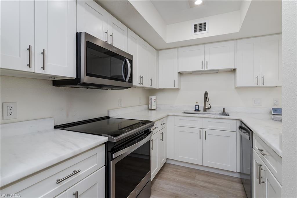 116 Clyburn Street, Unit C6 Marco Island, FL 34145 - Photo 9 of 32 a kitchen with stainless steel appliances granite countertop white cabinets a microwave a sink and dishwasher