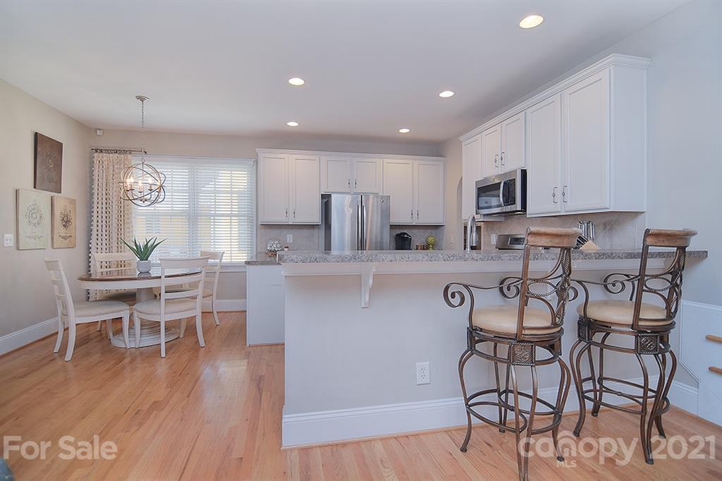 834 Promenade Walk Fort Mill, SC 29708 - Photo 14 of 45 a kitchen with stainless steel appliances kitchen island granite countertop a dining table chairs and granite counter tops