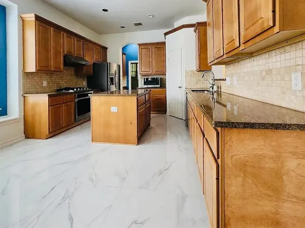 a kitchen with stainless steel appliances granite countertop a refrigerator a stove and a sink