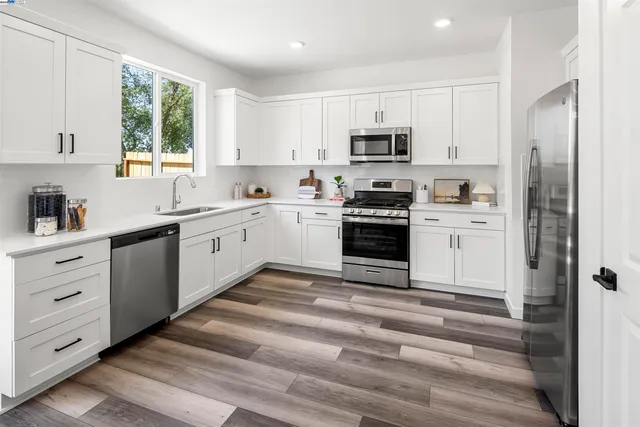 a kitchen with white cabinets stainless steel appliances and window