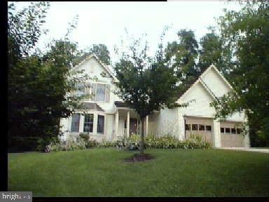 a front view of a house with a garden and trees