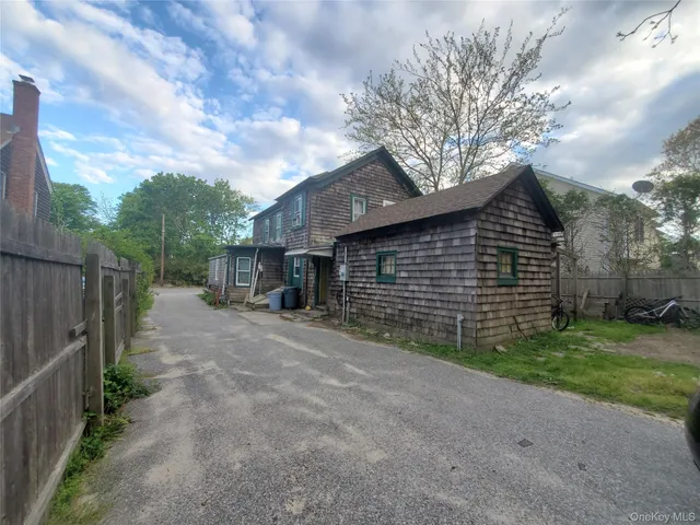 a view of a brick house next to a yard with big trees