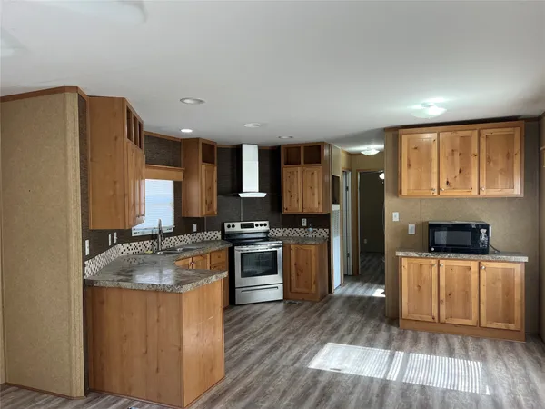 a kitchen with a refrigerator a stove top oven a sink dishwasher and wooden floor