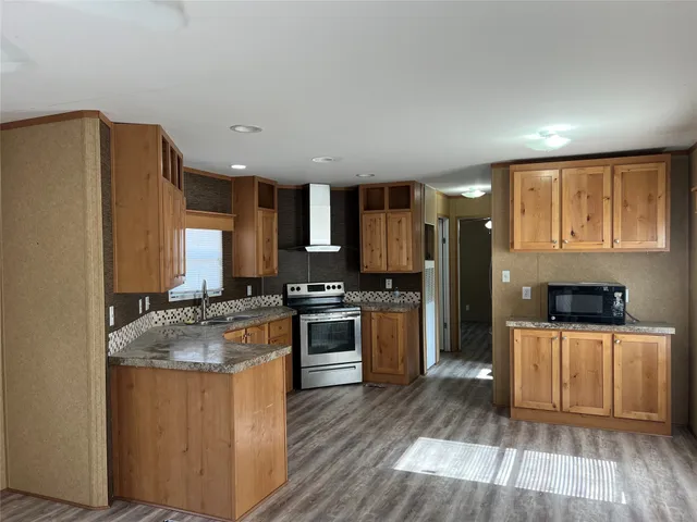 a kitchen with a refrigerator a stove top oven a sink dishwasher and wooden floor