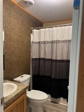a bathroom with a granite countertop toilet and a sink