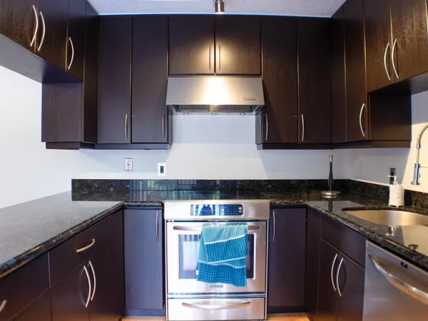 a kitchen with granite countertop wood cabinets stainless steel appliances and a sink