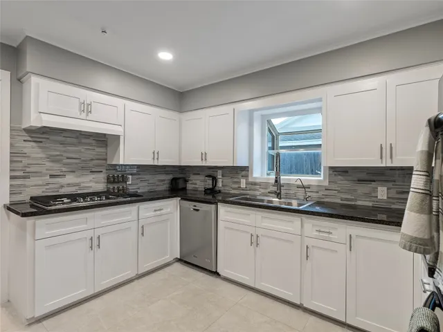 a kitchen with granite countertop white cabinets sink and stainless steel appliances
