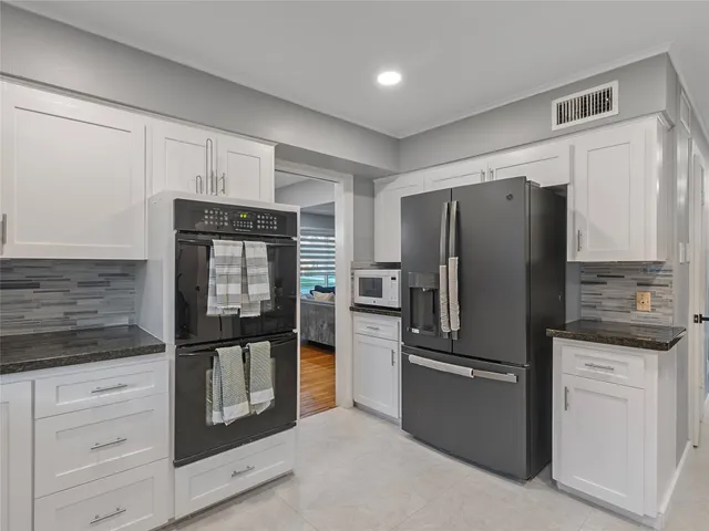 a kitchen with granite countertop a refrigerator and cabinets