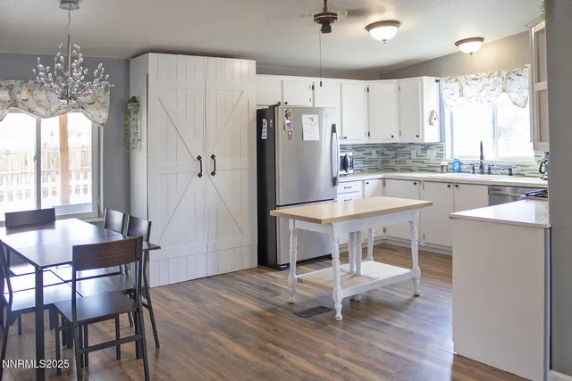 a kitchen with kitchen island a dining table chairs refrigerator and cabinets