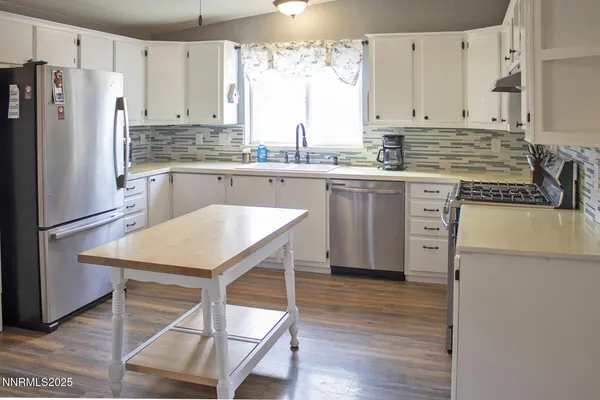 a kitchen with stainless steel appliances granite countertop white cabinets a sink and a refrigerator