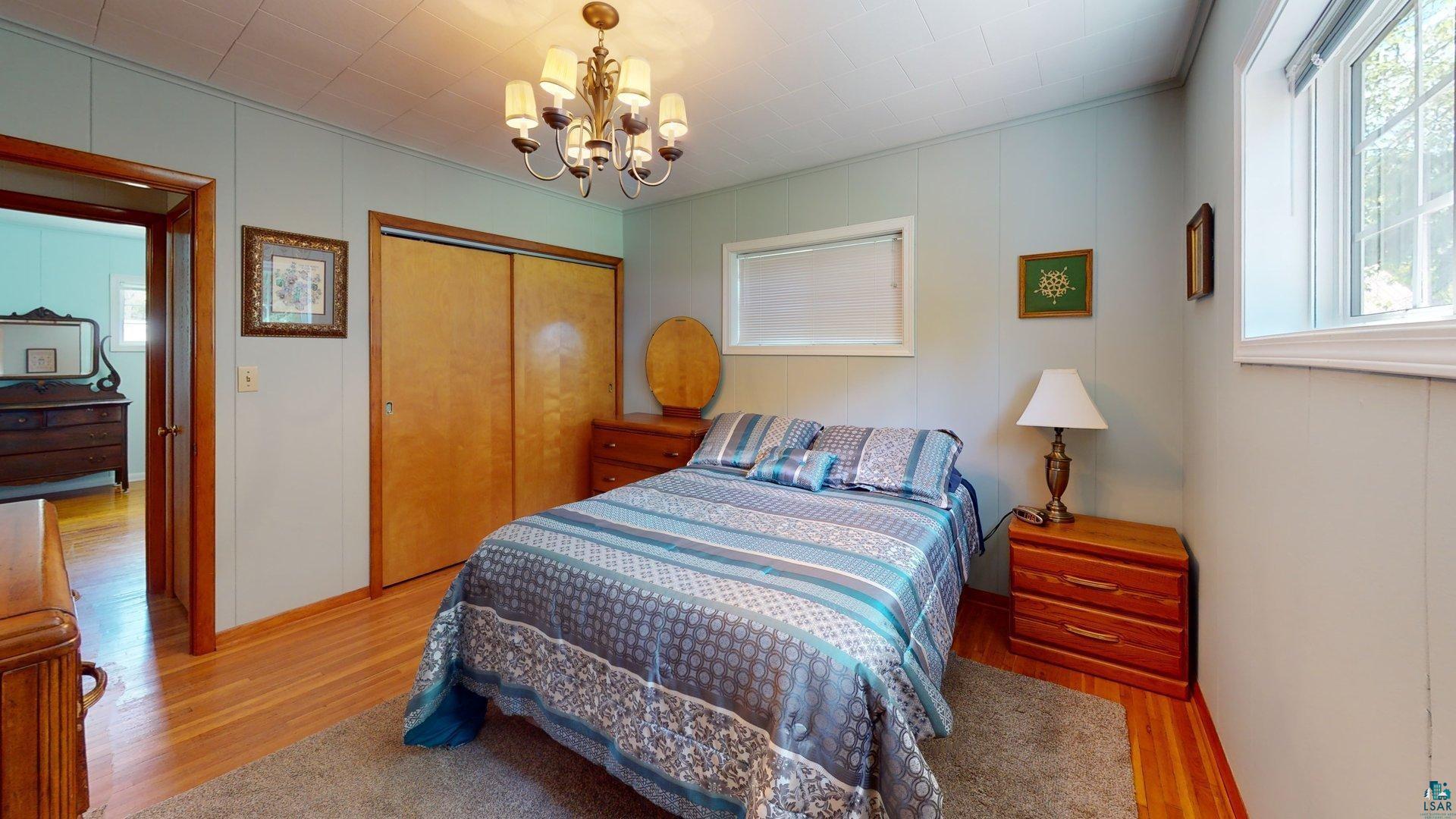 10614 Moose Lake Road Orr, MN 55771 - Photo 26 of 44 Interior room featuring wood-finish flooring, a wood-finish sliding door closet, and a chandelier with five frosted glass shades