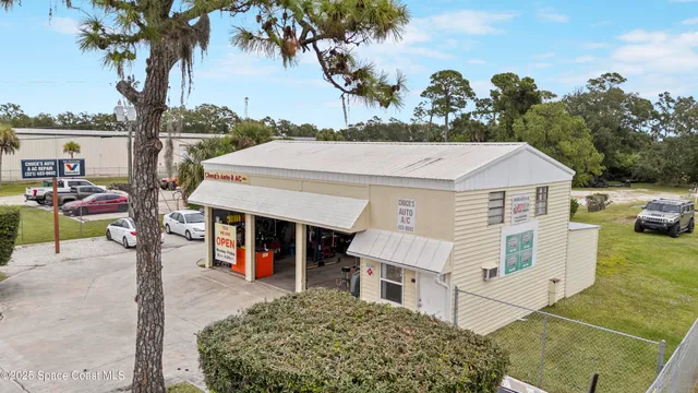 a view of a white house with a large tree and table chair