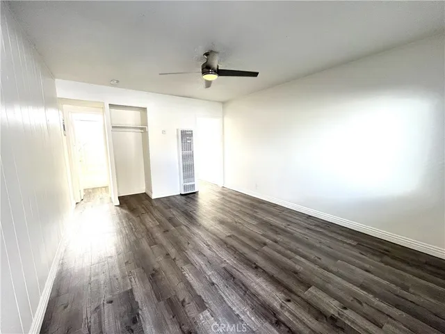an empty room with wooden floor ceiling fan and windows