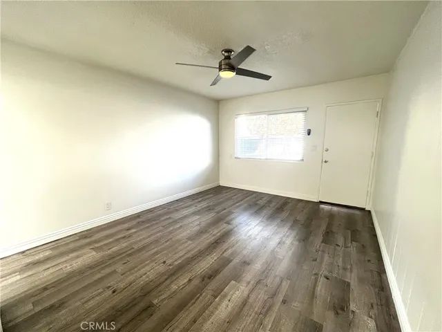 an empty room with wooden floor fan and windows