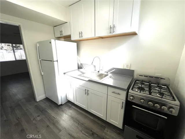a kitchen with granite countertop a sink stove and refrigerator