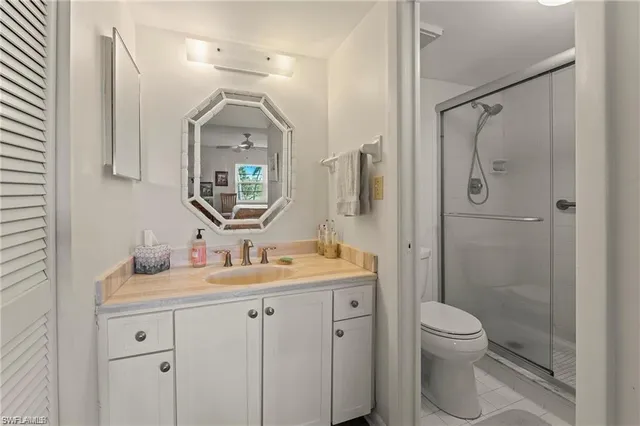 a bathroom with a toilet sink vanity granite and shower