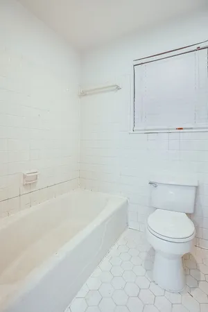a white toilet sitting next to a bath tub