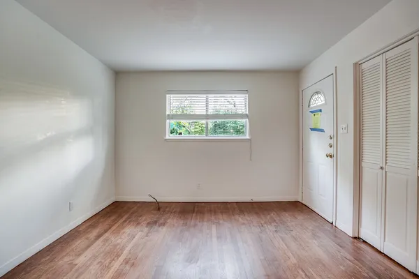 an empty room with wooden floor and windows