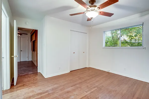 a view of empty room with wooden floor and fan