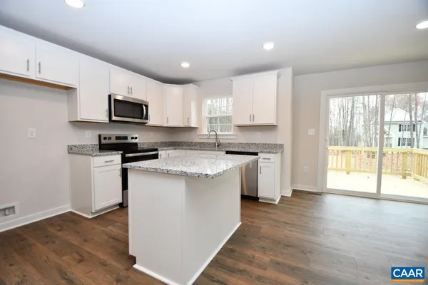 a kitchen with kitchen island granite countertop a stove top oven a sink a counter space and cabinets
