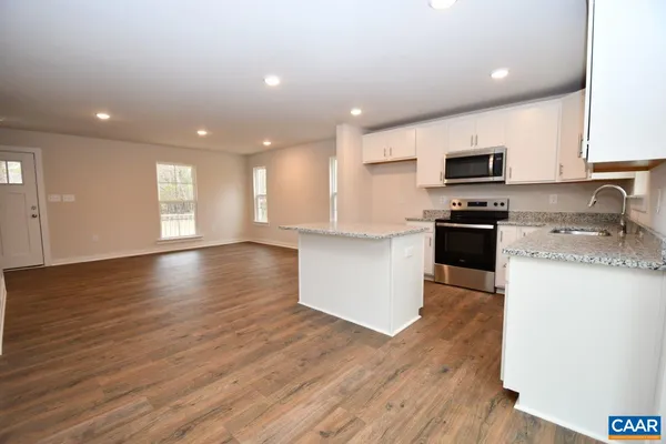 a kitchen with stainless steel appliances granite countertop a sink a stove top oven a counter space and cabinets