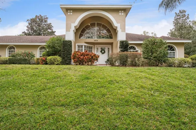 a view of a big house with a big yard and large tree