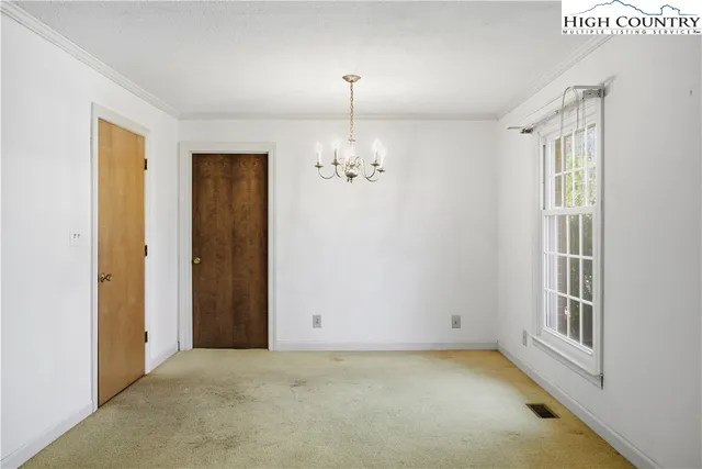 a view of a livingroom with a fireplace a chandelier and windows