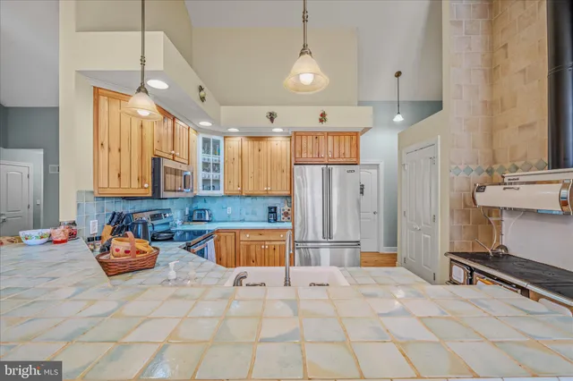 a kitchen with stainless steel appliances granite countertop a sink a stove a refrigerator cabinets and a kitchen island