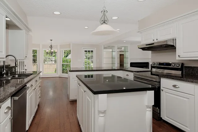 a kitchen with stainless steel appliances granite countertop a stove a sink and a refrigerator
