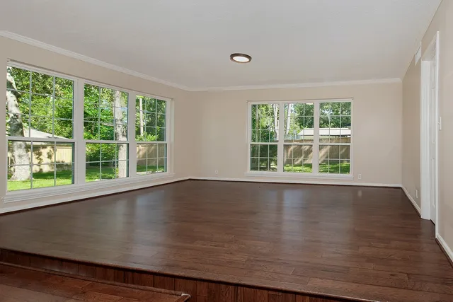 an empty room with wooden floor and windows