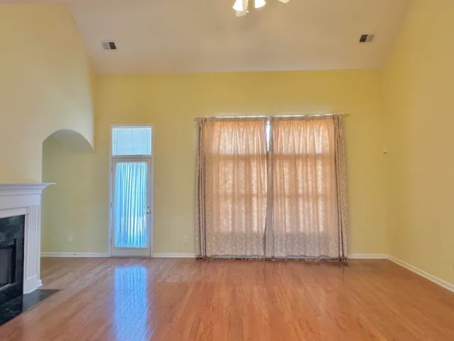 a view of an empty room with window and wooden floor