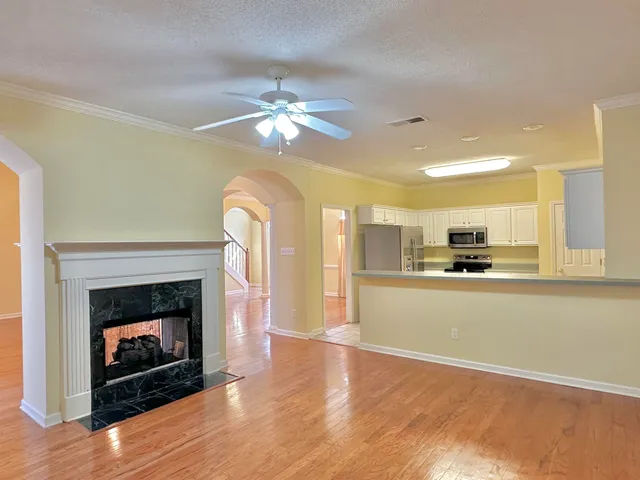 a living room with stainless steel appliances furniture a fireplace and a ceiling fan