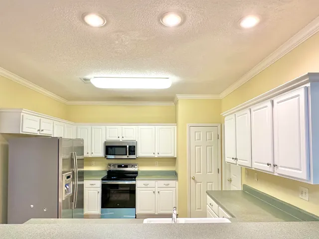 a kitchen with stainless steel appliances granite countertop a refrigerator and a stove top oven