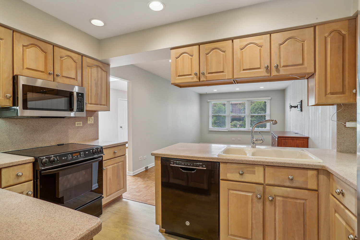 4010 Dundee Road Northbrook, IL 60062 - Photo 5 of 14 a kitchen with stainless steel appliances granite countertop a sink dishwasher stove and microwave with wooden cabinets