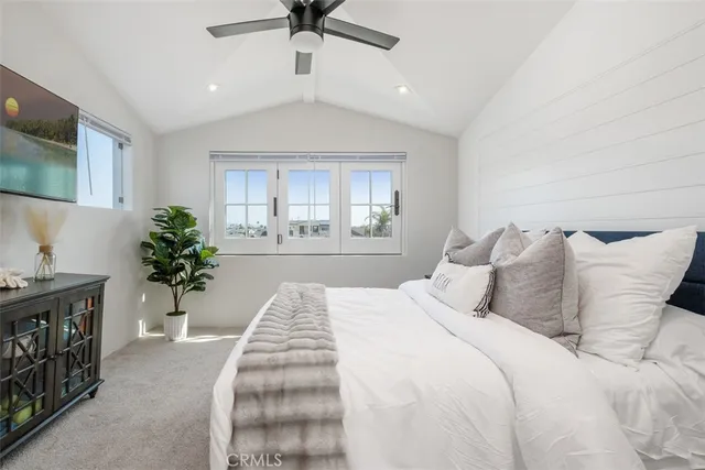 a spacious bedroom with a large bed and a flat tv screen