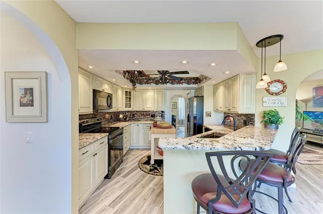 a kitchen with stainless steel appliances kitchen island granite countertop a sink stove and refrigerator