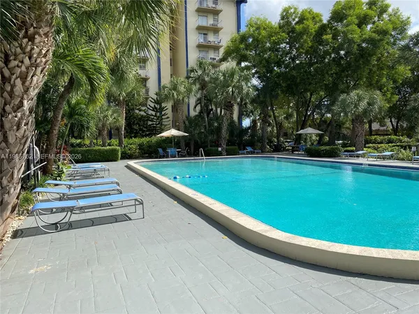 a view of a swimming pool with a yard and trees